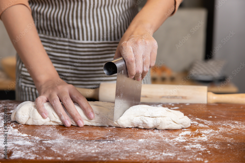 Baker Hand Cutting Raw Dough with a Knife