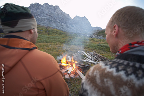 2 male friends sitting at a camp fire in Greenland photo