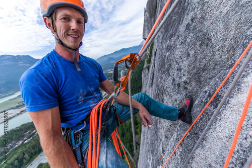 Man resting while rock climbing hanging on rope with ascender photo