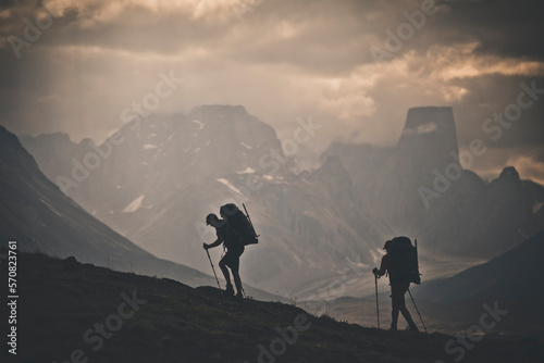 Silhouette of two backpackers hiking with rugged mountain view. photo