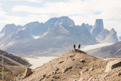 Two hikers stand on high mountain ridge in Akshayak Pass Baffin Island photo