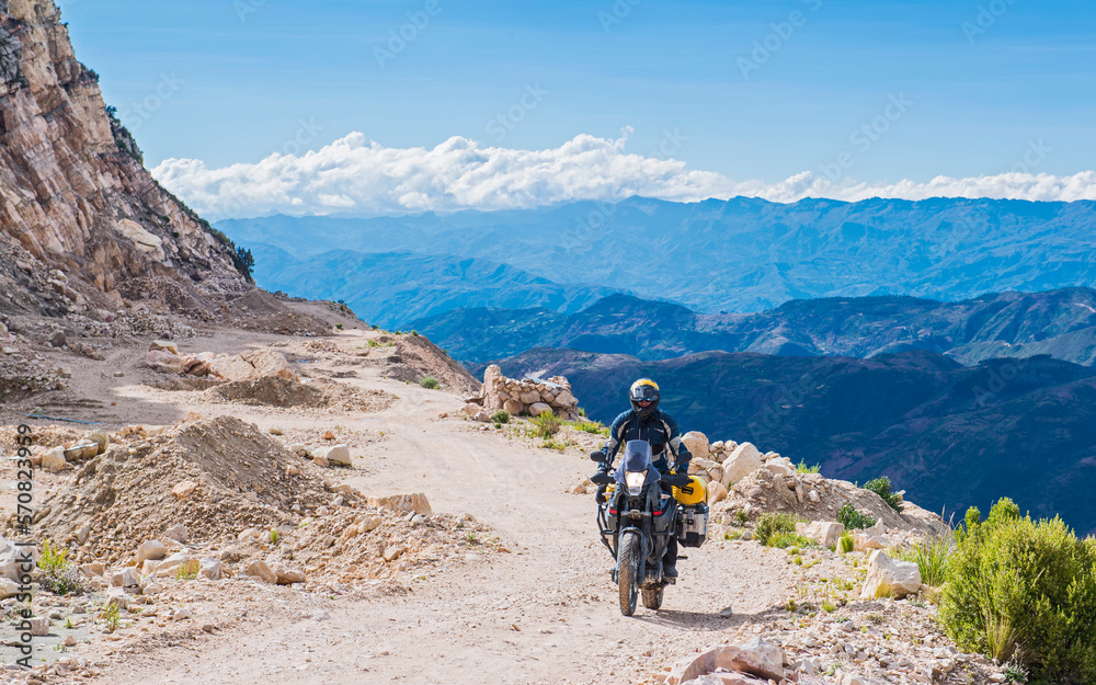 Man riding touring motorcycle on gravel road in Bolivia Man riding touring motorcycle on gravel road in Bolivia