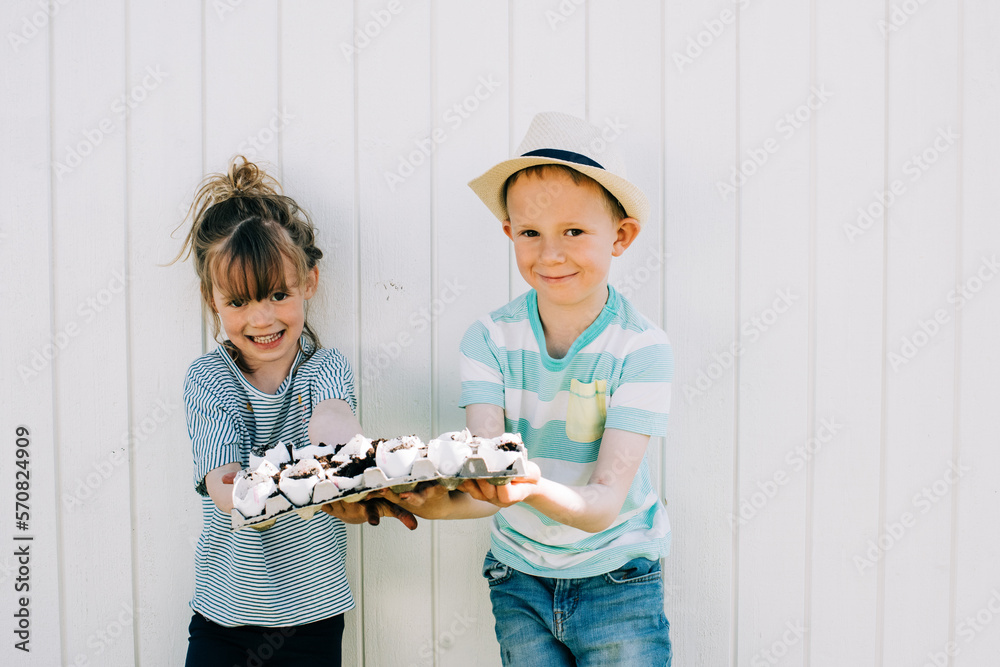 siblings holding up their egg shells that they planted seeds into siblings holding up their egg shells that they planted seeds into