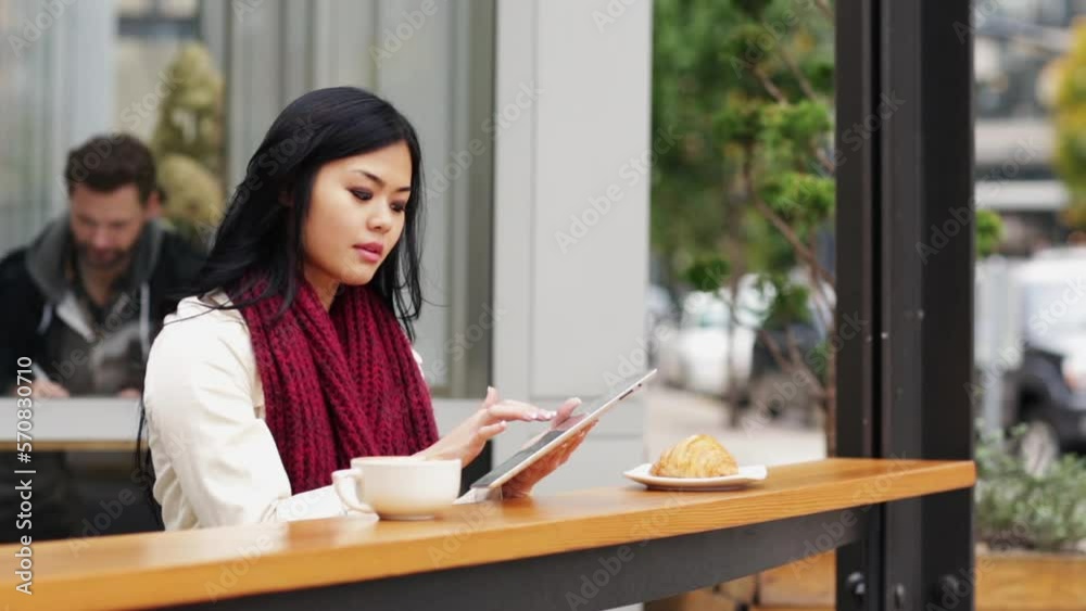 Woman using electronic tablet while sitting outside café Woman using electronic tablet while sitting outside café