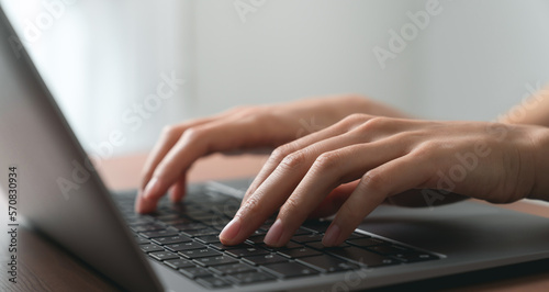 Hand using computer laptop and touching mouse on the table.