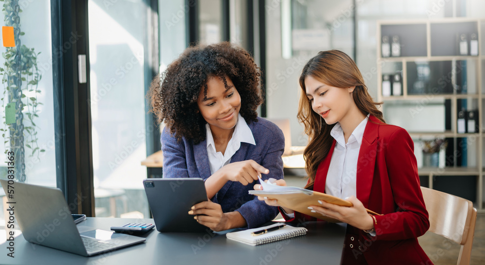 Two  businesswoman discuss investment project working and planning strategy with tablet laptop computer in modern office.