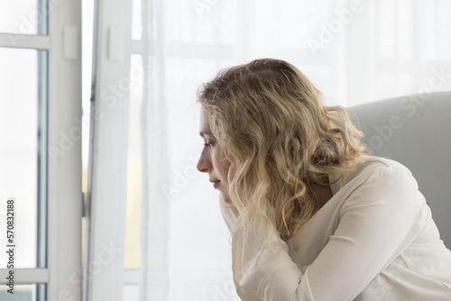 Free Download Pensive dreamy young woman lost in thoughts sitting in home armchair at window, looking away, thinking on problems, difficult decision, leaning head, getting bored, lazy. Side view - GFXLoad