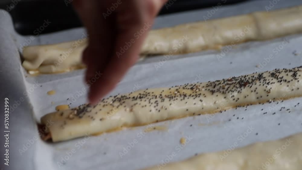 Tracking shot of crop person spilling seeds on raw pastry rolls Tracking shot of crop person spilling seeds on raw pastry rolls