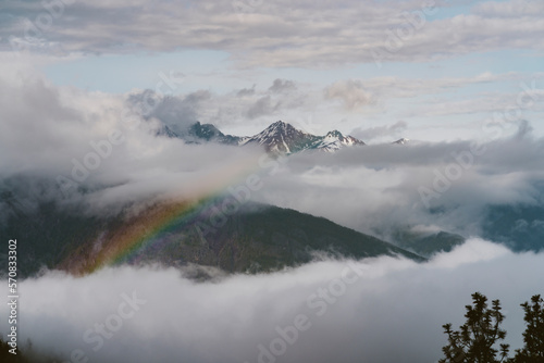 A rainbow appears in the clouds after a rain storm in the mountains
