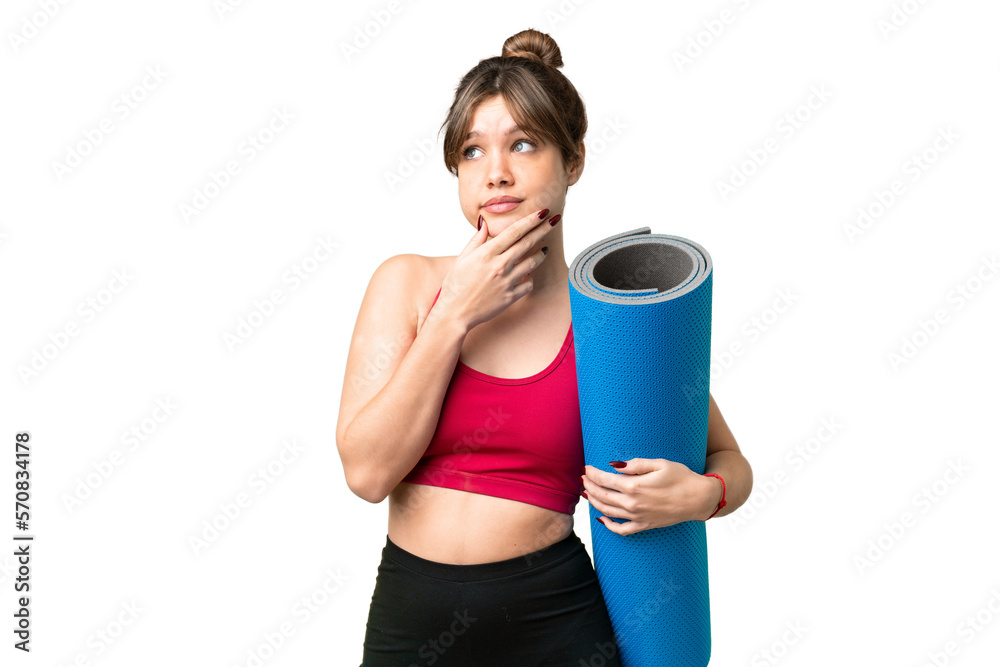Young sport girl going to yoga classes while holding a mat over isolated chroma key background having doubts Young sport girl going to yoga classes while holding a mat over isolated chroma key background having doubts