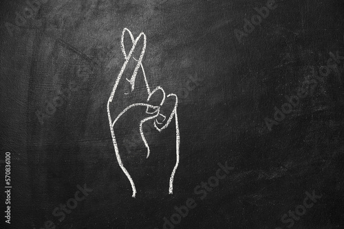 Obraz na płótnie Hand with crossed fingers drawn in chalk on a black board w salonie