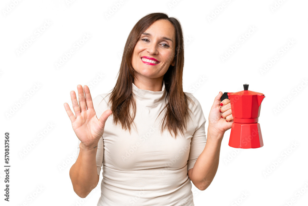 Middle-aged caucasian woman holding coffee pot over isolated background saluting with hand with happy expression Middle-aged caucasian woman holding coffee pot over isolated background saluting with hand with happy expression