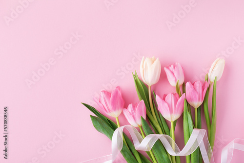 Fototapeta Naklejka Na Ścianę i Meble -  Spring tulip flowers with ribbon on pastel pink background top view. Greeting card for International Women Day, Mother day. Flat lay.
