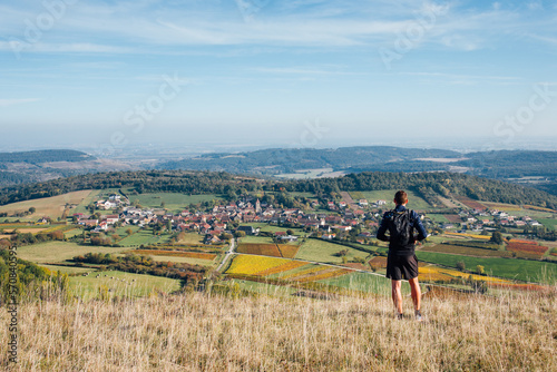 Vue de dos d'un homme sportif regardant un panorama de vigne en automne. Un coureur faisant une pose devant un paysage viticole automnal. Admirer le vignoble de Bourgogne © david