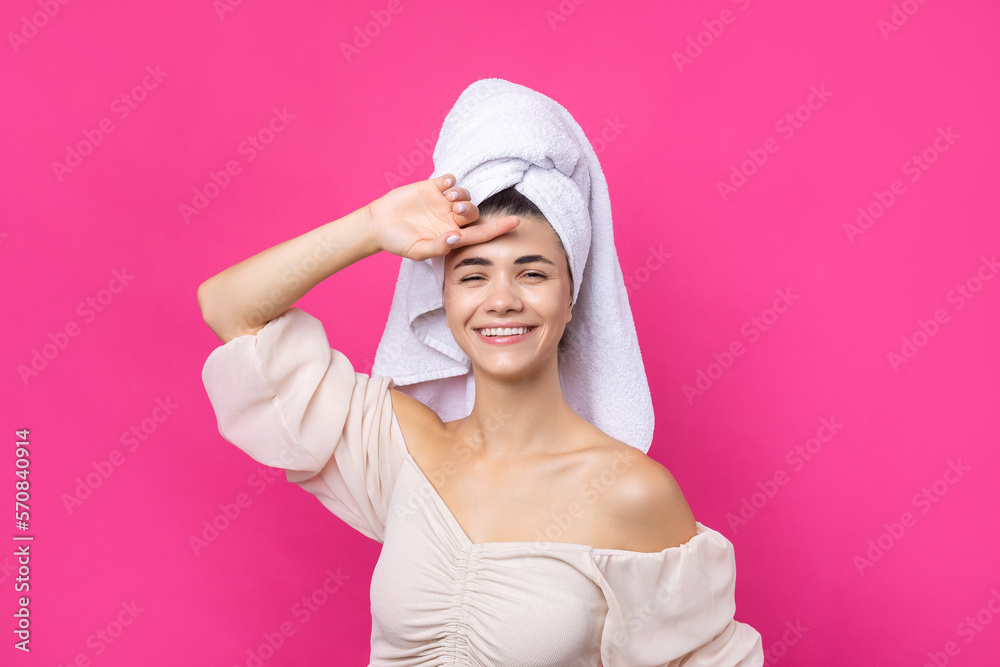 Portrait of young beautiful woman after bath. Beauty face of a cheerful attractive girl with towel on head against a pink background. Portrait of young beautiful woman after bath. Beauty face of a cheerful attractive girl with towel on head against a pink background.