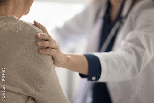 Hand of geriatrician doctor touching shoulder of elderly patient woman, giving empathy, comfort, psychological support, assistance, explaining serious diagnosis of illness. Close up cropped shot