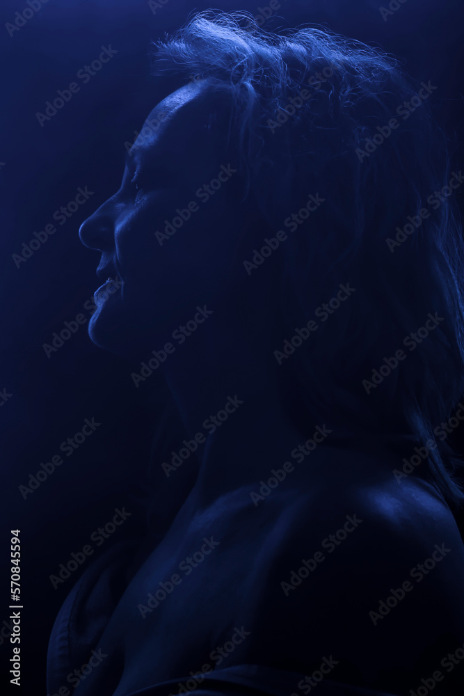 Backlit portrait of a middle-aged blond woman in blue light