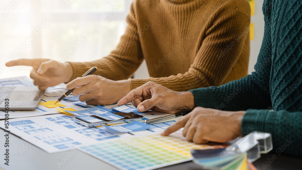 UI developer and ui designer brainstorming about mobile app interface wireframe design with customer breif and color code at office. UI developer and ui designer brainstorming about mobile app interface wireframe design with customer breif and color code at office.