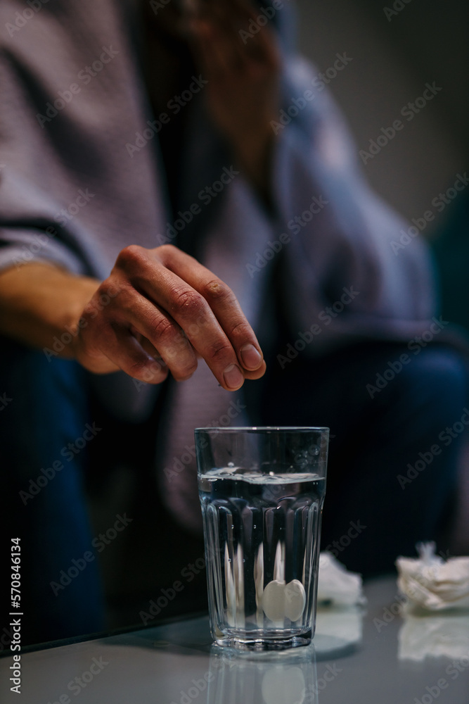 Close-up of the man's hand putting aspirin paracetamol pill splashing into a glass of water. Close-up of the man's hand putting aspirin paracetamol pill splashing into a glass of water.