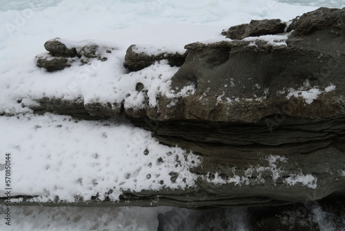 texture of porous stones on the beach covered by snow, nature, natural phenomena, brown-gray stones photo