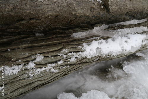 texture of porous stones on the beach covered by snow, nature, natural phenomena, brown-gray stones photo