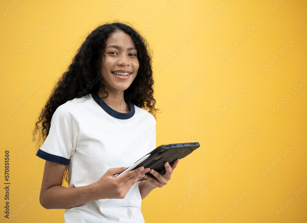 Photo of young attractive African American with black hair happy positive woman hold pc tablet isolated over yellow color background. Photo of young attractive African American with black hair happy positive woman hold pc tablet isolated over yellow color background.
