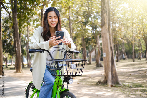 Young asian woman using smart phone on a bicycle. technology and lifestyle concept.