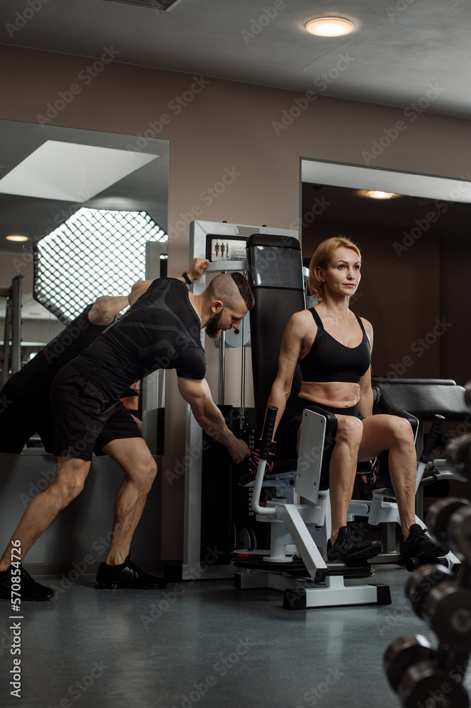 Middle aged sporty woman is doing exercises with a personal coach in the gym Middle aged sporty woman is doing exercises with a personal coach in the gym
