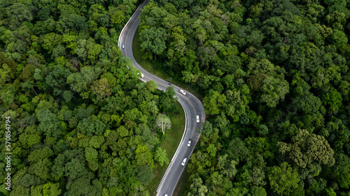 Aerial view green forest with car on the asphalt road, Car drive on the road in the middle of forest trees, Forest road going through forest with car. © Kalyakan
