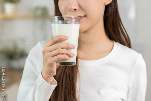 Health care, pretty asian young woman, girl drinking a glass of white fresh, dairy milk for calcium, vitamin wholesome good nutrition in morning at kitchen home. lifestyle, product healthy people.