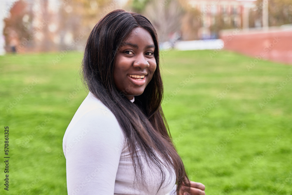 portrait of a young african american girl with straight hair looking at the camera outdoors.