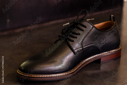 Side view of black formal leather shoe on a black floor. Mens formal shoes