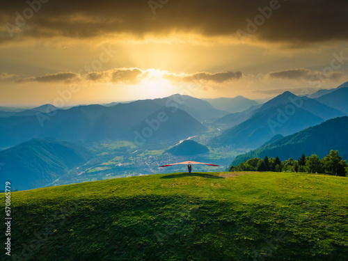 Hang glider ready to launch from the green meadow in the mountains photo