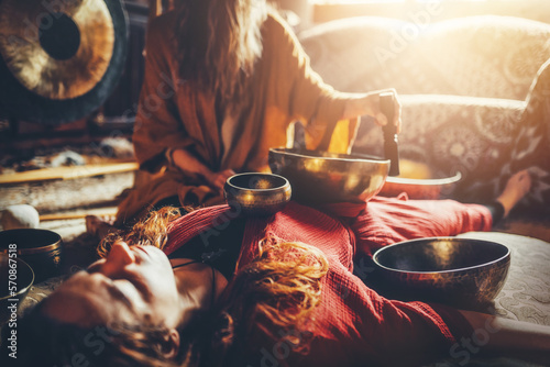 beautiful woman playng on tibetan bowl. Woman on music therapy. ceremonial space. photo