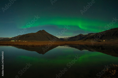 Aurora Borealis or Northern lights the amazing wonder of nature in the dramatic skies of Iceland. Night landscape with the green light in a beautiful dance reflected like a mirror