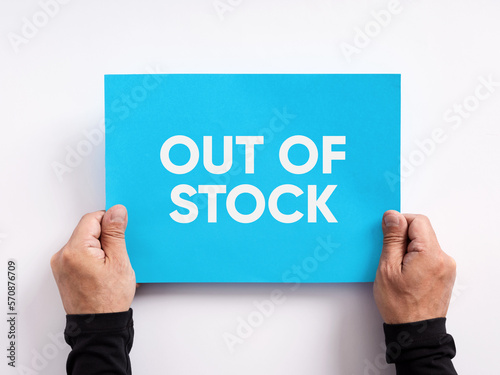 Male hand holding a blue paper with the message out of stock. photo