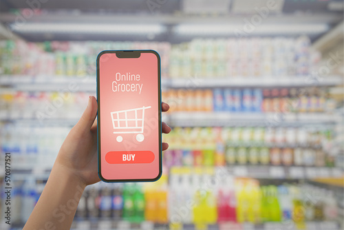 hand holding mobile with grocery online on screen with blur supermarket background. 3D illustration