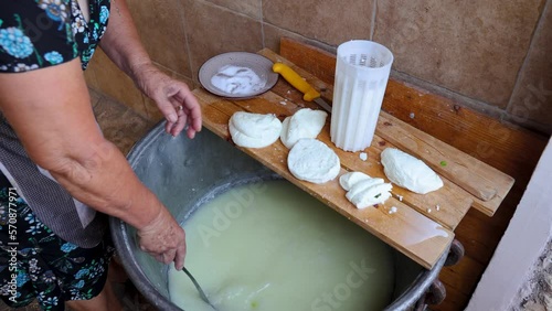 Mrs Sofia cuts Halloumi chesse in Sofia And Andreas Traditional House in Letymbou village, Cyprus, 4k photo