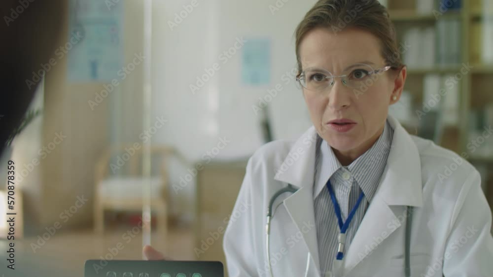 Female doctor explaining brain CT scan on digital tablet to patient during medical consultation in clinic Female doctor explaining brain CT scan on digital tablet to patient during medical consultation in clinic