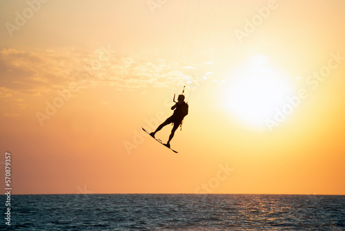 Silueta de hombre volando, haciendo kitesurf al atardecer