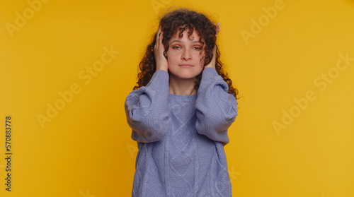 Dont want to hear and listen. Frustrated annoyed irritated curly haired woman covering ears gesturing No, avoiding advice ignoring unpleasant noise loud voices. Young girl on studio yellow background © Andrii Iemelianenko