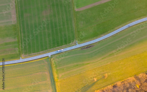 birds eye view of road going through green fields at sunset