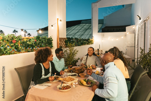 Happy African family dining together on house patio photo