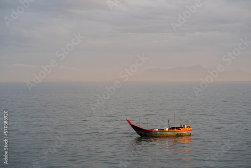 Cuadro en lienzo Fisherman sailing the wooden boat in the middle of the ocean during sunrise