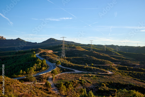 Fotografia Row of electricity pylons along an asphalt mountain road on a sunny day