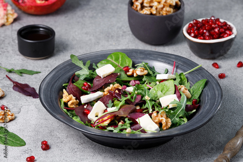 Salad mix with fresh spinach, walnuts, pomegranate and white cheese on a stone table. © Sergey