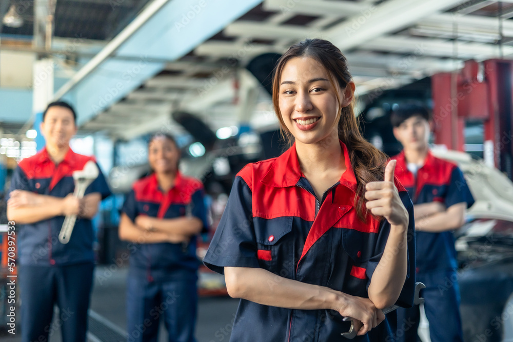 Obraz premium Asian automotive engineer people wear helmet work in mechanics garage.young auto mechanic in uniform is looking at camera and smiling examining car.