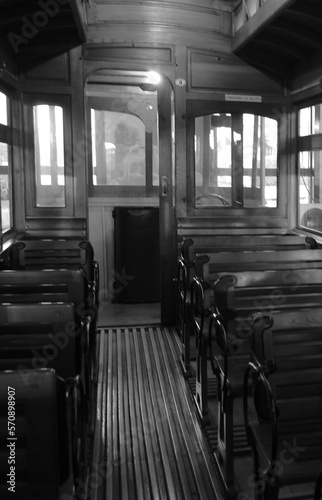 Seating in the interior of an old passenger train in black and white. 