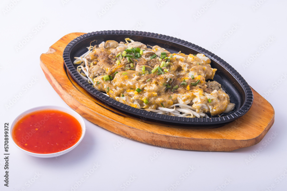 Crispy fried mussel pancake with chili sauce on the wooden plate .