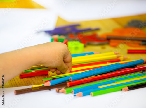 close-up of a child's hand drawing with colored pencils on a white sheet of paper